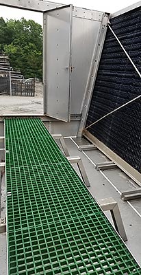 Custom Fabricated FRP Green Walkway Grate Grid withe USA Made Stainless Steel Mount Above a Cold Water Basin.  Custom Metal Fabricated Stainless Steel Vertical Door in the Background